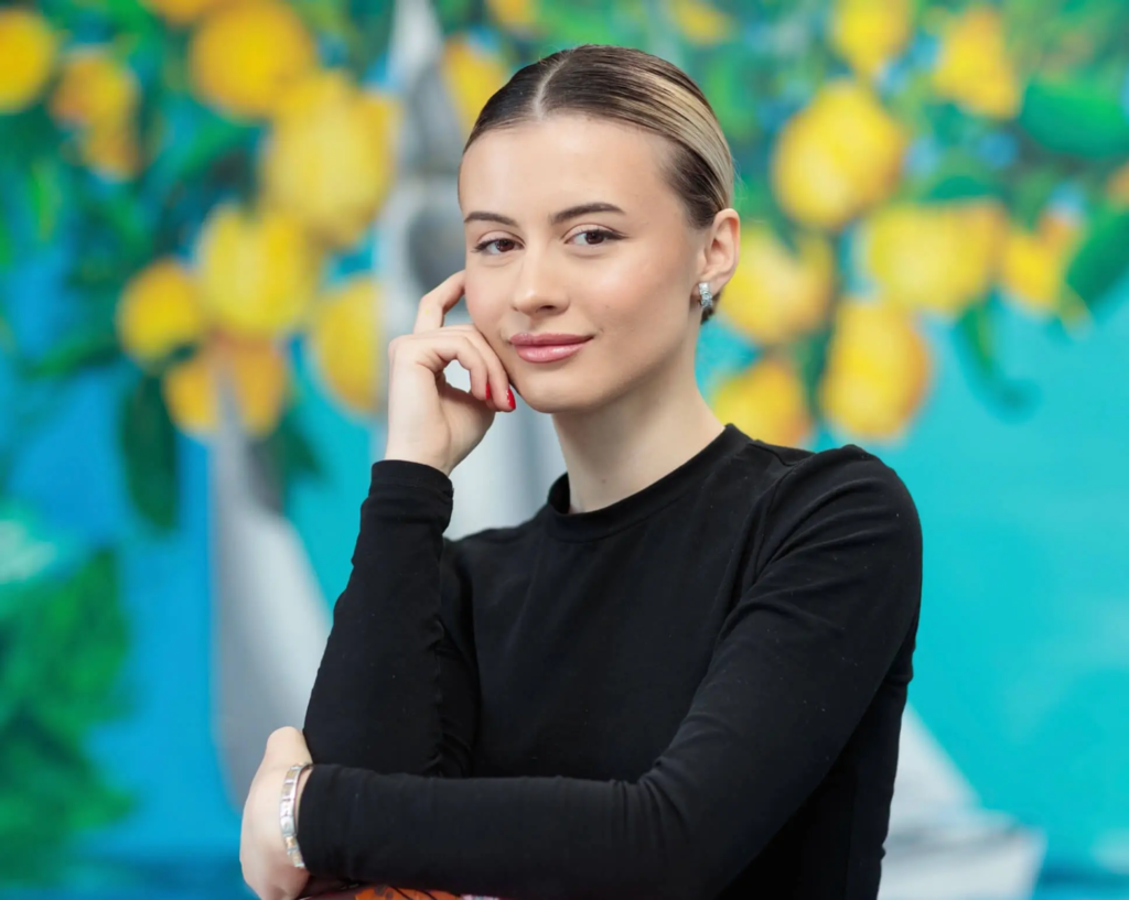 Portrait of Silvi The Artist in front of a vibrant abstract painting, highlighting her contemporary Bulgarian art style.